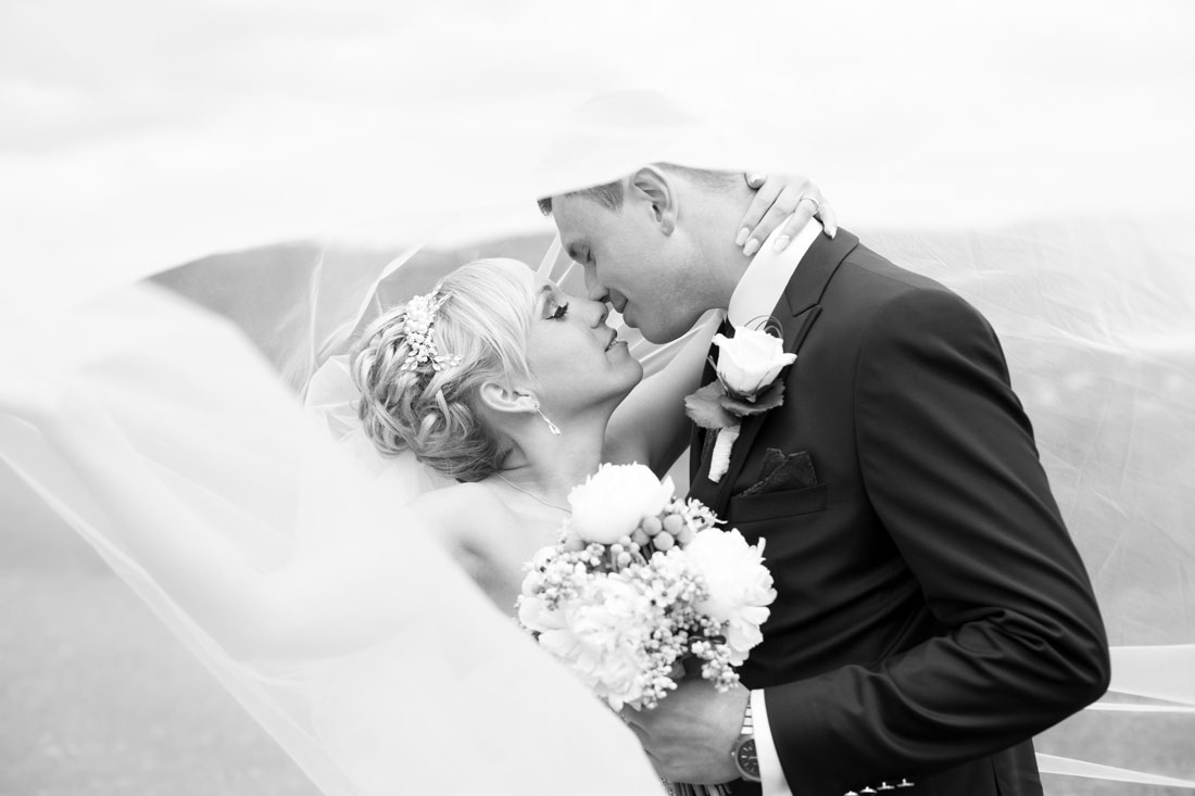 Hochzeit-Burgruine-Windeck-Brautpaar-Porträit-Foto-unter-dem-Schleier-Umarmung-Fruehlingshochzeit-langer-Schleier-Hochzeitskuss