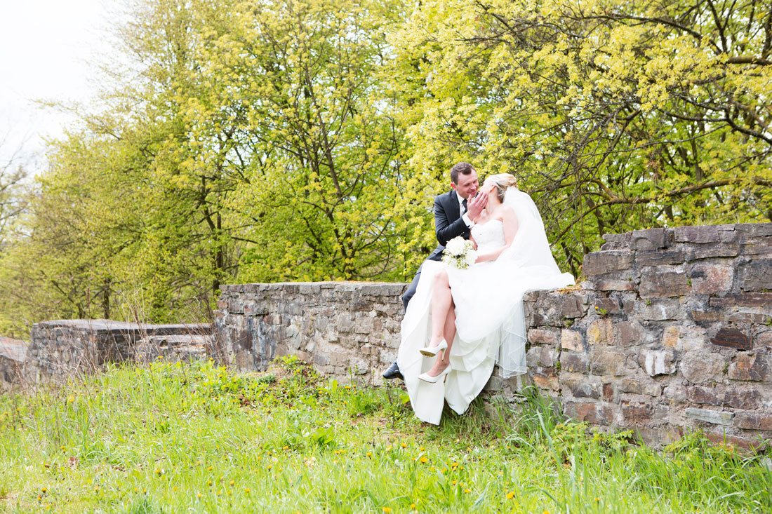 Hochzeit-Burgruine-Windeck-Burgmauer-Brautpaar-sitzt-auf-der-Mauer-Fruehlingshochzeit