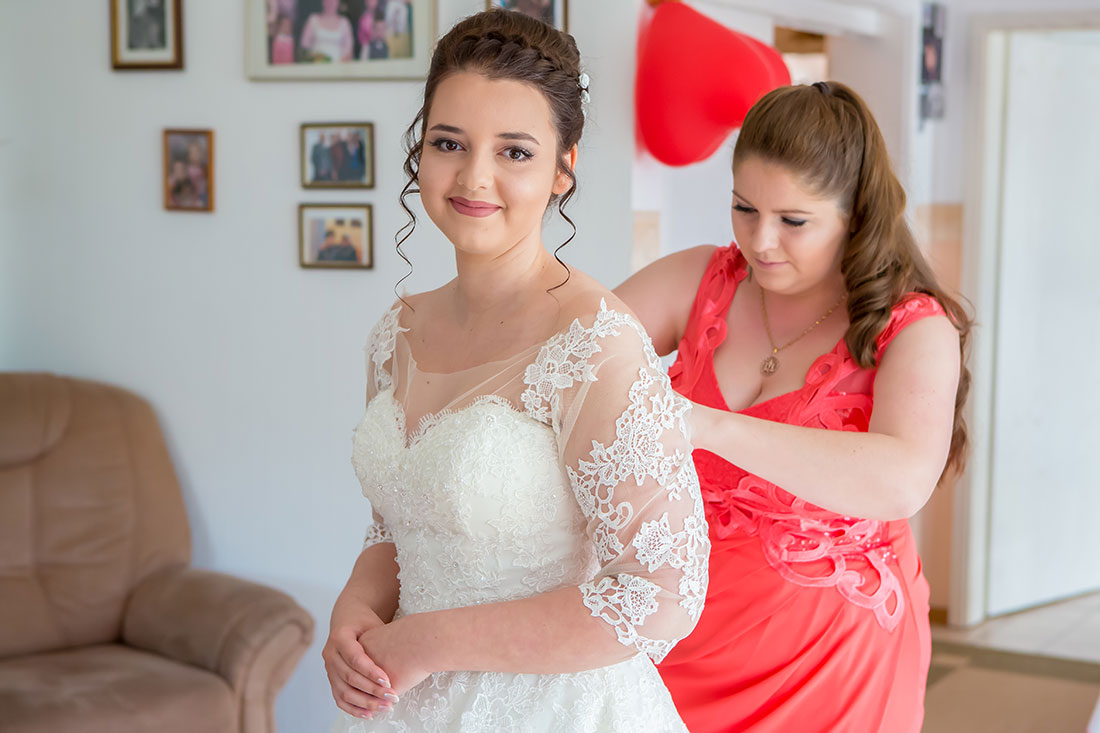 Hochzeit-in-Braunschweig-getting-ready-der-Braut-Trauzeugin-hilft-Brautkleid-zuschnüren-Vorbereitung-Sergej-Metzger-Hochzeitsvideo-Hannover-Fotograf-Hildesheim